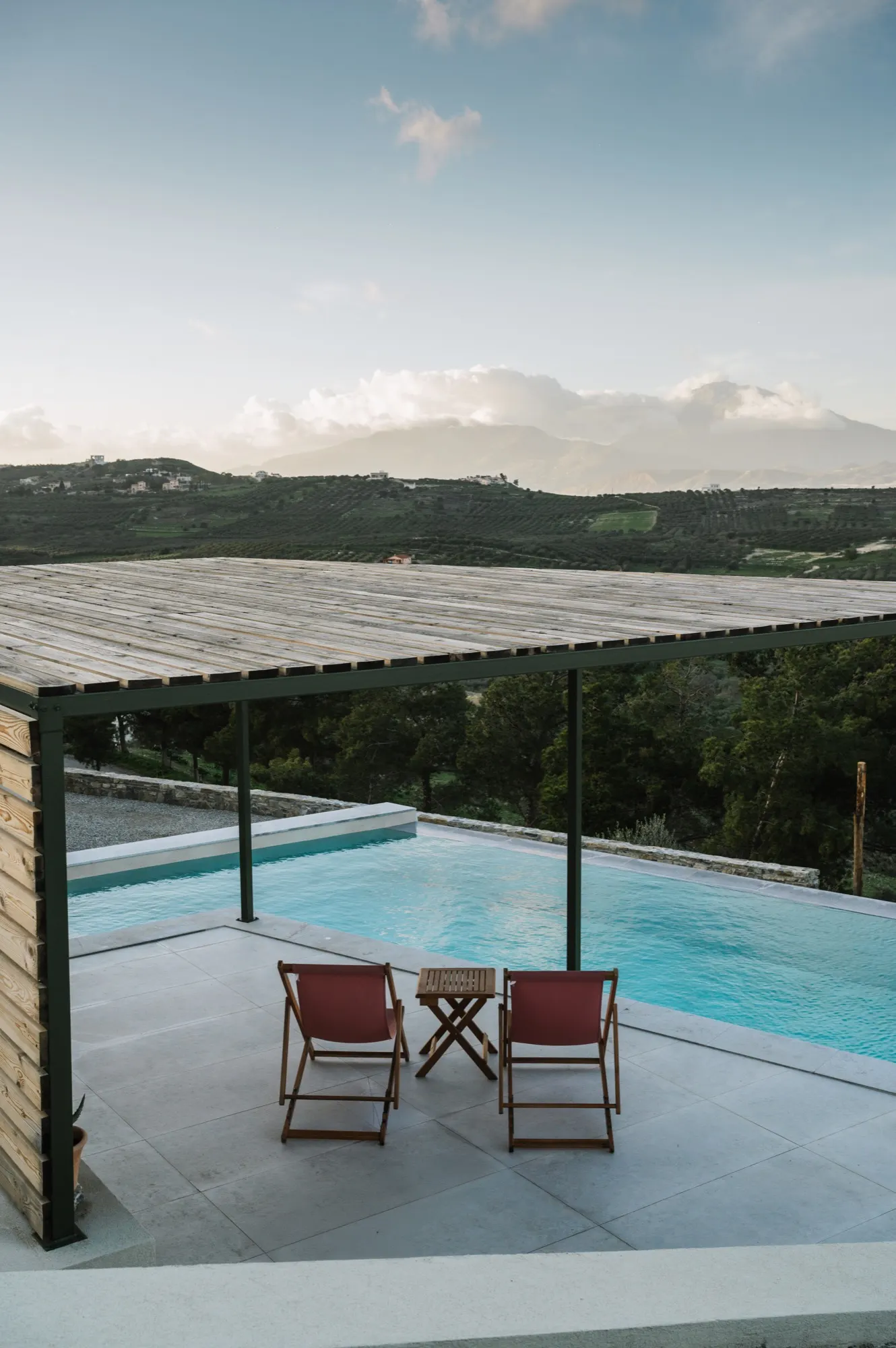 Pergola beside the infinity pool with two deck chairs, mountains in the distance